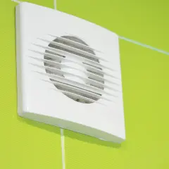 Aspiratore elicoidale o centrifugo bianco montato su una parete verde brillante.