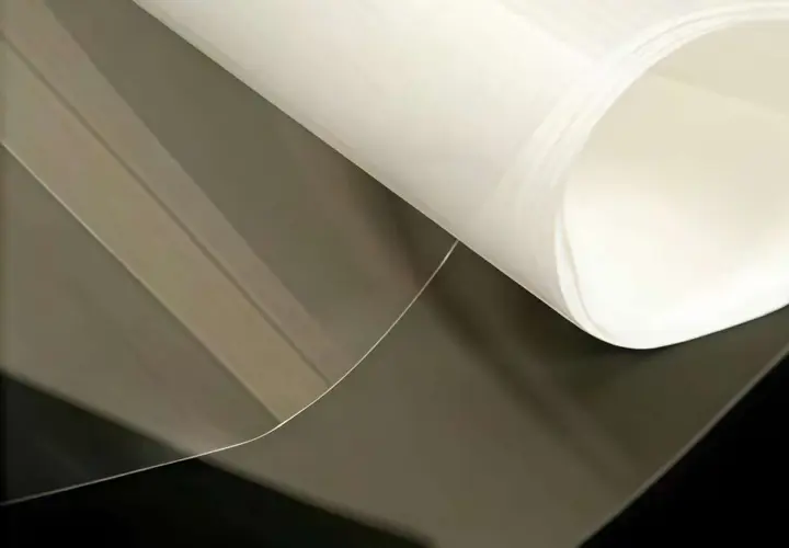Foglio di materiale riflettente luce, trasparente e bianco, con pieghe morbide.